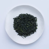 White plate of dark green loose leaf Ippodo Tea Rimpo gyokuro tea leaves on white table