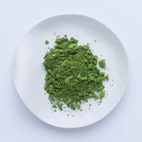 Bright green loose Japanese Ippodo Tea Shoin matcha powder on white plate on white table