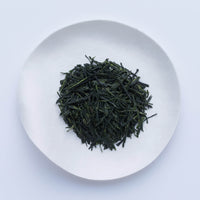 Loose leaf darker green rolled dried Ippodo Tenka-Ichi Gyokuro premium Japanese green tea on white plate on white table