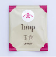 Single individual cream package of One-Cup Teabag of Ippodo Gyokuro Tea with pink corners and logo on shiny circle, Japanese