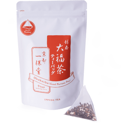 Pyramid shaped teabag of genmaicha green tea and roasted rice beside package of Obukucha Good Fortune Tea Teapot-Size Teabags