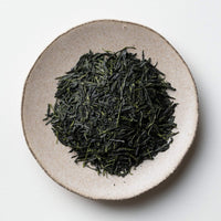 Loose leaf darker green rolled dried Ippodo Organic Gyokuro premium Japanese green tea on white plate on white table