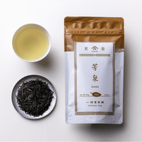 Teacup of brewed light green sencha tea alongside plate of dark tea leaves and bronze packaging for Ippodo Hosen Sencha
