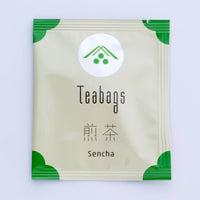 Single individual cream package of One-Cup Teabag of Ippodo Sencha Tea with green corners and logo on shiny circle, Japanese