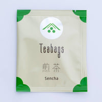 Single individual cream package of One-Cup Teabag of Ippodo Sencha Tea with green corners and logo on shiny circle, Japanese