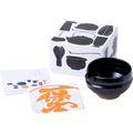 Black matcha tea bowl with serving spout alongside fukin tea cloth, illustrated instruction kit and tea utensil decorated box