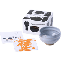 White matcha tea bowl with serving spout alongside fukin tea cloth, illustrated instruction kit and tea utensil decorated box