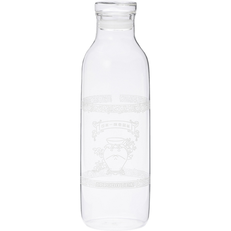 A clear glass bottle with a narrow neck and wide body. It appears empty and has some etched or printed design on its surface, though the details aren't clearly visible. The bottle has a simple, cylindrical shape typical of water or juice bottles, with a slight lip at the top where a cap would typically be placed. The glass is transparent and clean.
