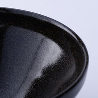 Close-up of shiny textured speckled surface of dark ceramic Mino-yaki matcha tea bowl
