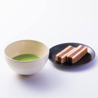 Cream with white brush stroke mino-yaki Chawan tea bowl with frothy green matcha and three red bean wafer desserts on plate