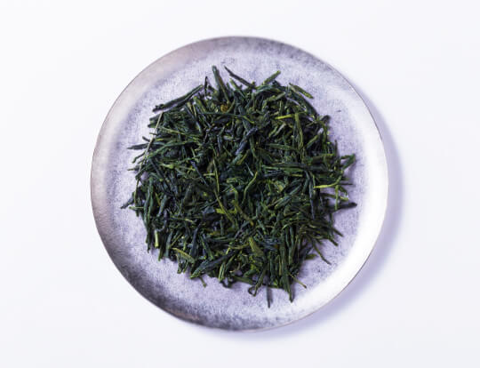 loose leaf dark green rolled dried Ippodo Tea Co. Gyokuro premium Japanese green tea on silver plate on white background