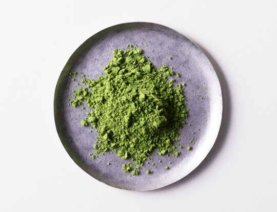loose bright green finely ground milled Ippodo Tea Co. Japanese Matcha tea powder on silver plate on white table