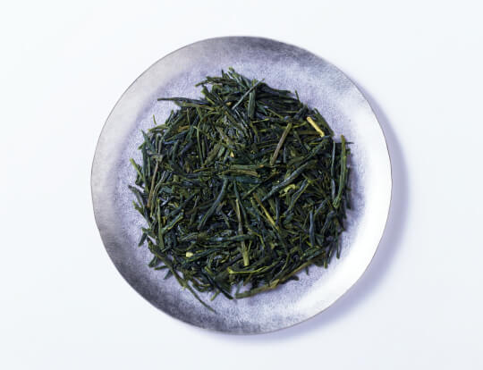 Loose leaf dark green rolled dried Ippodo Tea Co. Sencha premium Japanese green tea on silver plate on white background