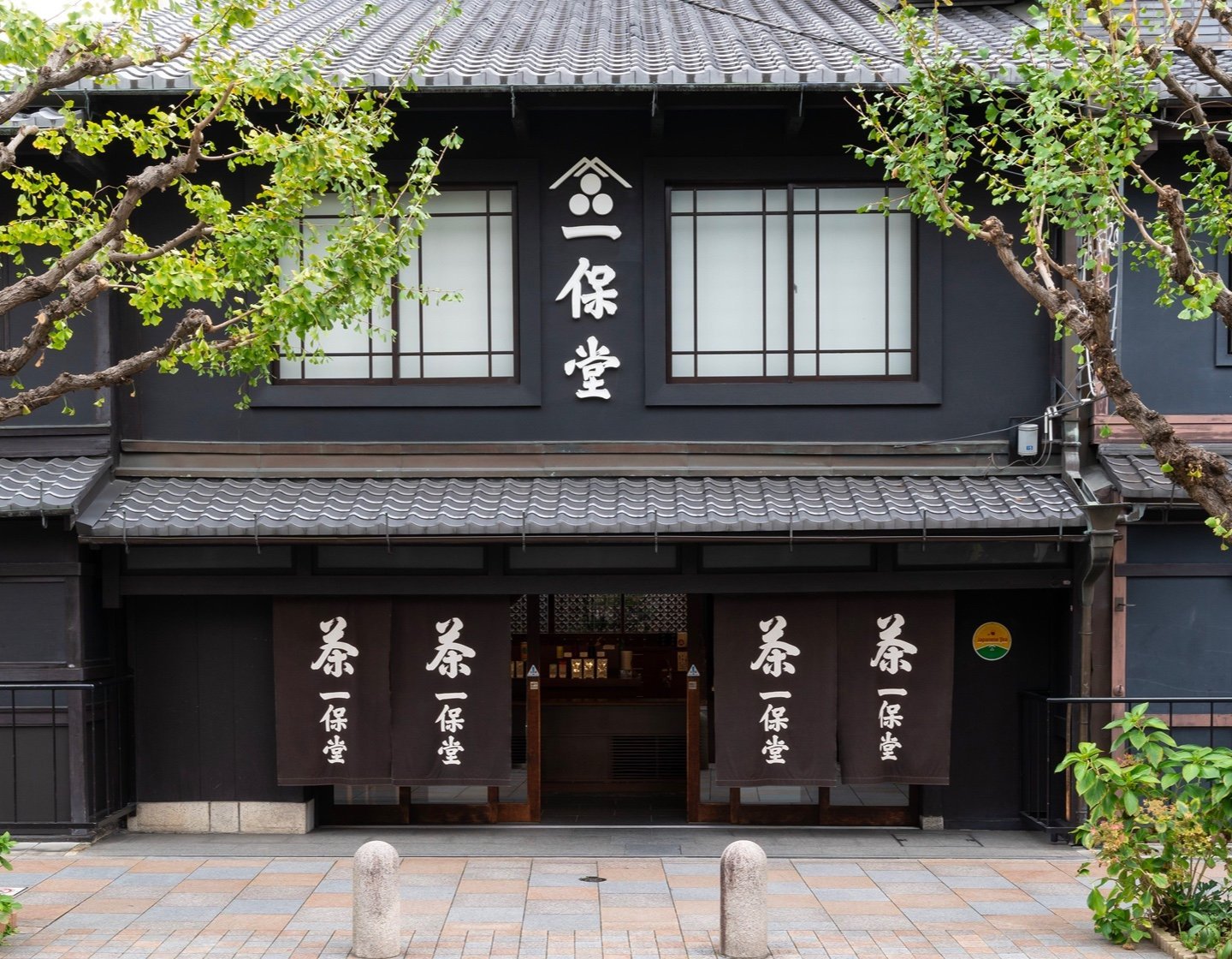 Black storefront of Ippodo Tea's flagship store, tearoom and headquarters in Kyoto, Japan with lush cherry blossom trees