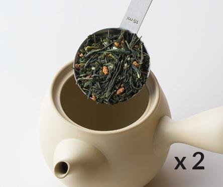 Scooping Genmaicha dried green tea with golden toasted rice with silver tablespoon into Ivory artisan-made ceramic teapot