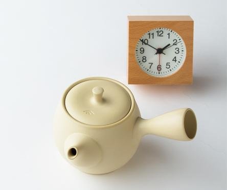 Ivory Ippodo Tea Co. Tokoname-yaki ceramic kyusu teapot set beside orange clock timer on white table