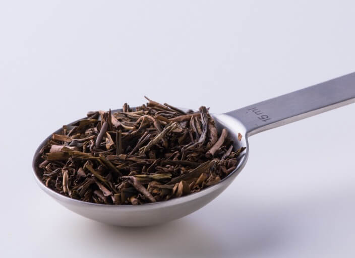 Silver tablespoon filled with dried rolled Ippodo Hojicha premium roasted Japanese green tea leaves