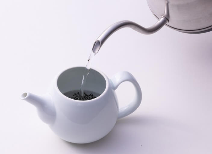 Pouring hot water from silver kettle into white Hakuji ceramic Ippodo Tea Co. Japanese kyusu teapot