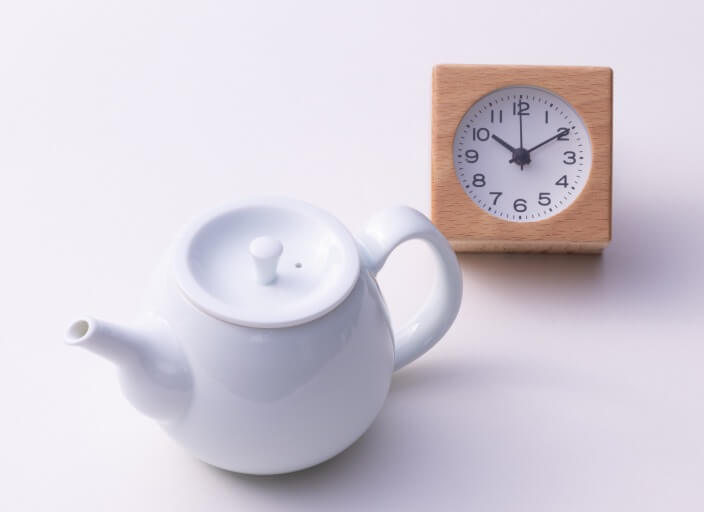Ippodo Tea Co. white Hakuji ceramic kyusu teapot set beside orange clock timer on white table