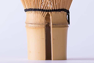 Bamboo handle of a chasen with a vertical crack below the black thread weaving