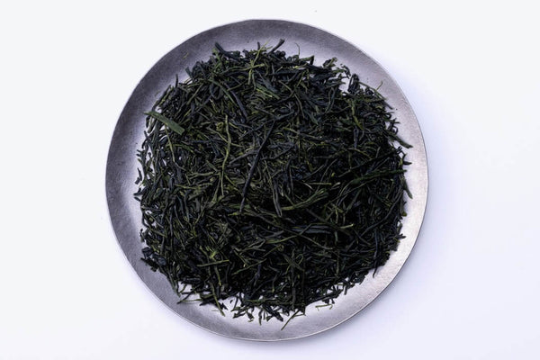 Loose leaf dark green rolled dried Ippodo Tea Co. Gyokuro premium Japanese green tea on silver plate on white background