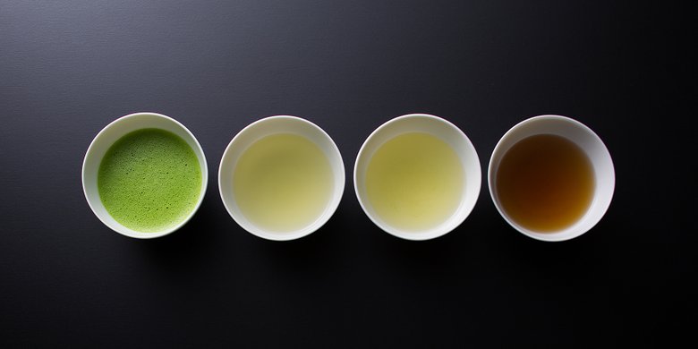 Four cups of freshly brewed Japanese tea — matcha, gyokuro, sencha, and bancha — arranged in a row