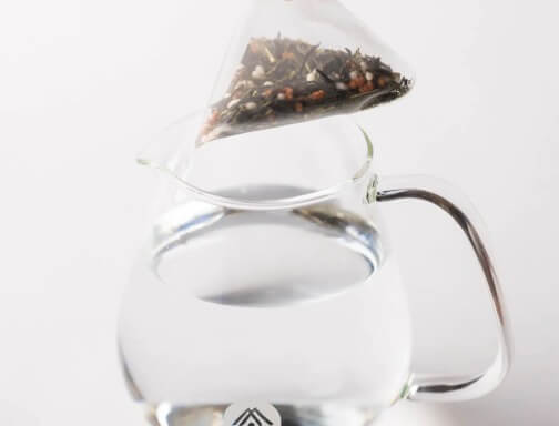 Genmaicha teabag in a glass carafe steeping in cold water.
