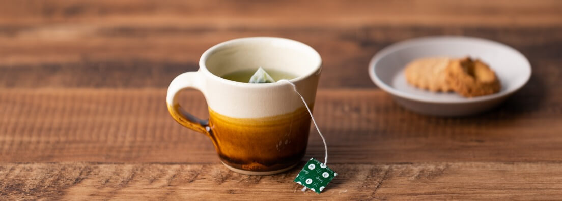 Ceramic mug with teabag steeping inside on a wooden table