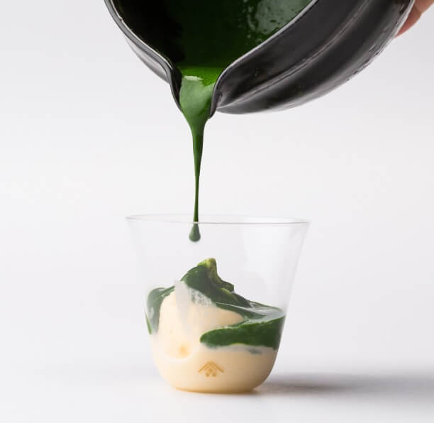 koicha thick matcha being poured over vanilla ice cream in a glass cup