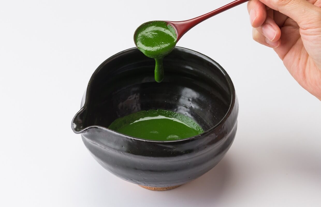 koicha thick matcha being poured into a black teabowl