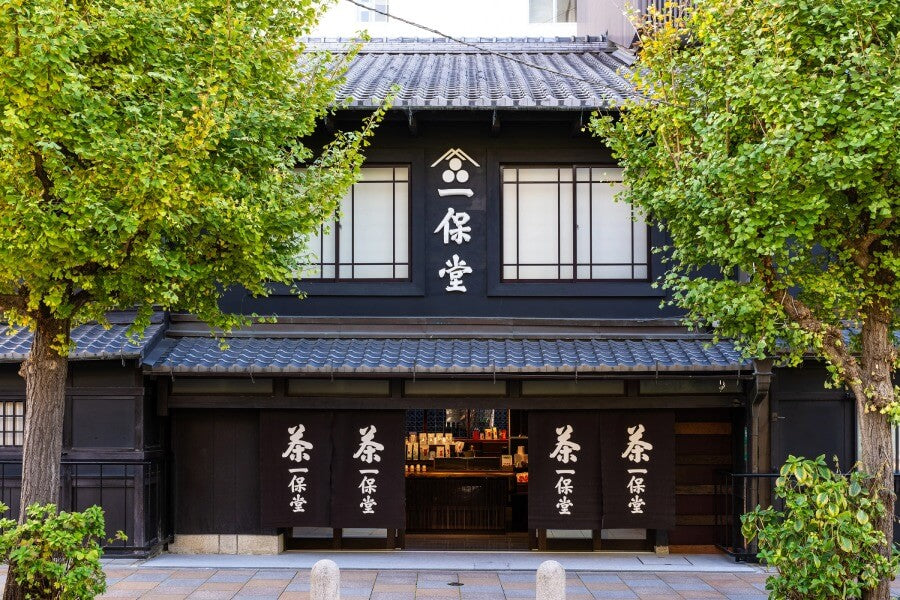 Front of of Ippodo Tea's flagship store, tearoom and headquarters black storefront in Kyoto, Japan with outdoor lit neon sign