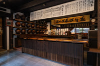 Front of of Ippodo Tea's flagship store, tearoom and headquarters black storefront in Kyoto, Japan with outdoor lit neon sign