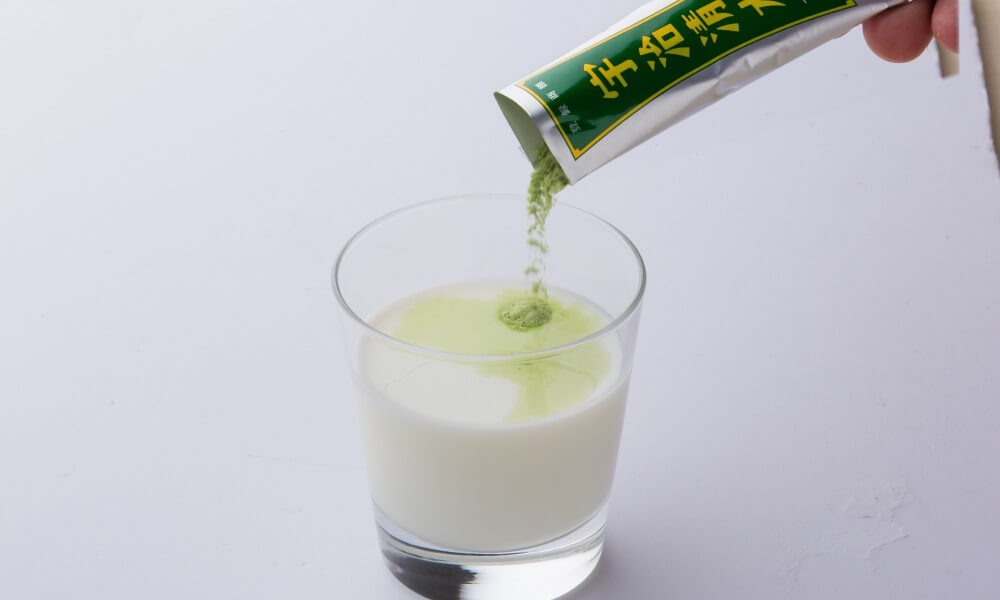 Picture of uji-shimizu sweetened matcha powdered being poured into a glass with milk